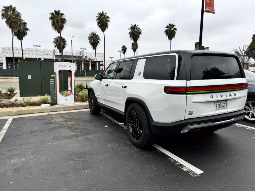 Glacier White Gen 1 Rivian R1S using a Tesla supercharger